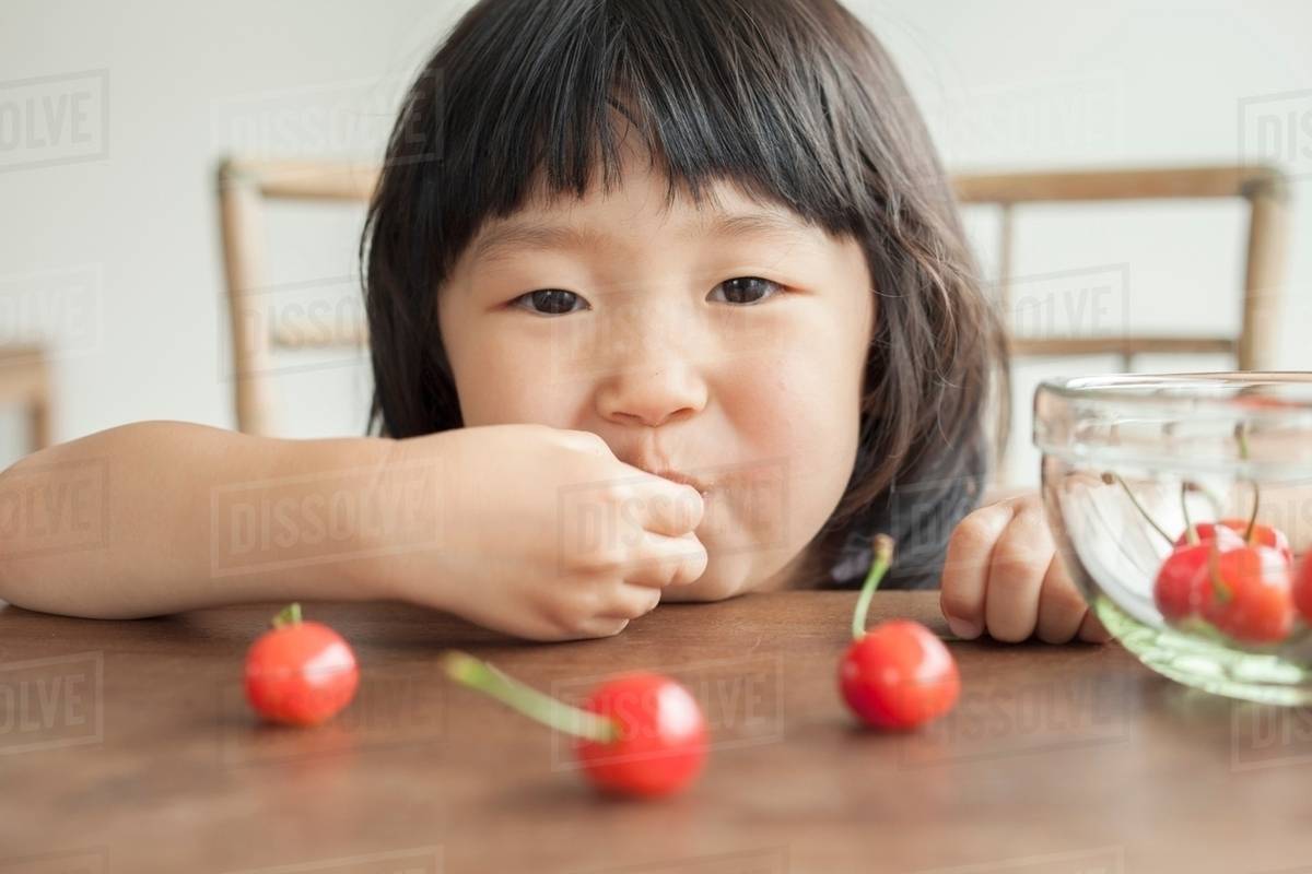 Girl eating cherries, portrait Stock Photo Dissolve