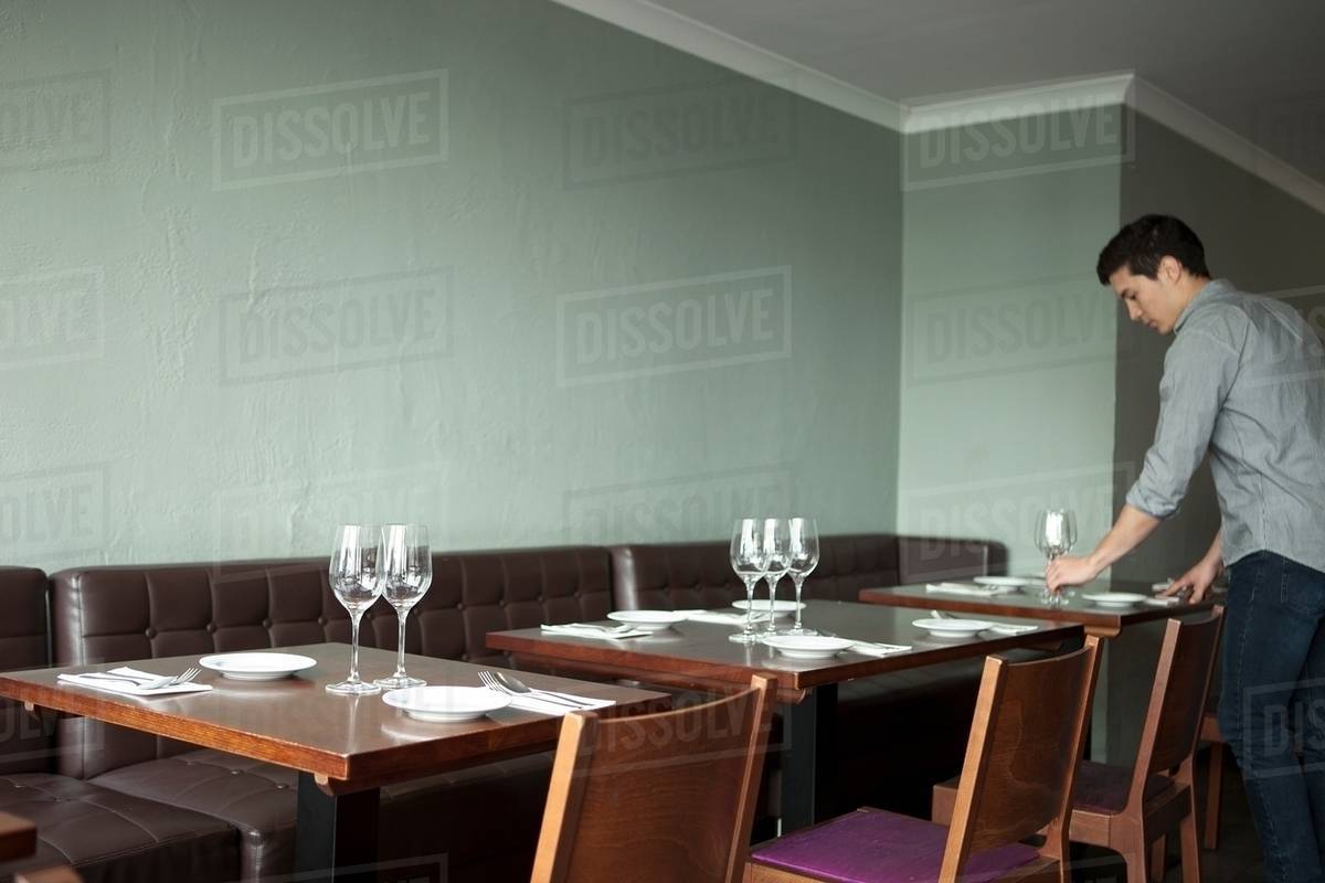 Waiter setting table in restaurant Stock Photo Dissolve