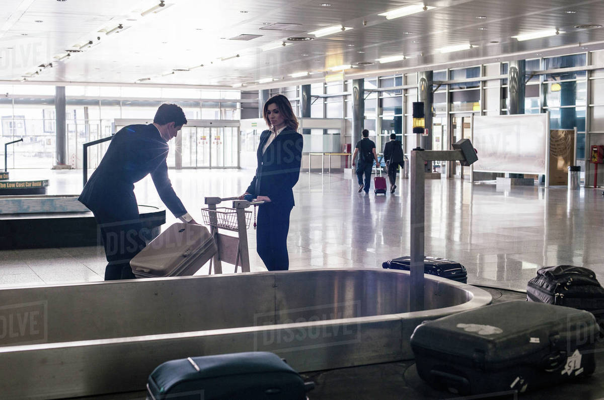 Businesspeople in airport at baggage reclaim Stock Photo Dissolve