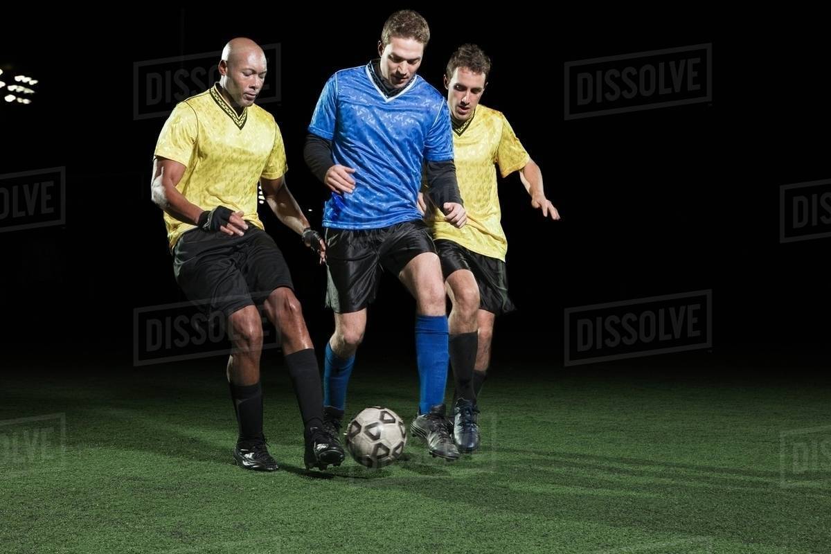 Soccer players tackling on pitch Stock Photo Dissolve