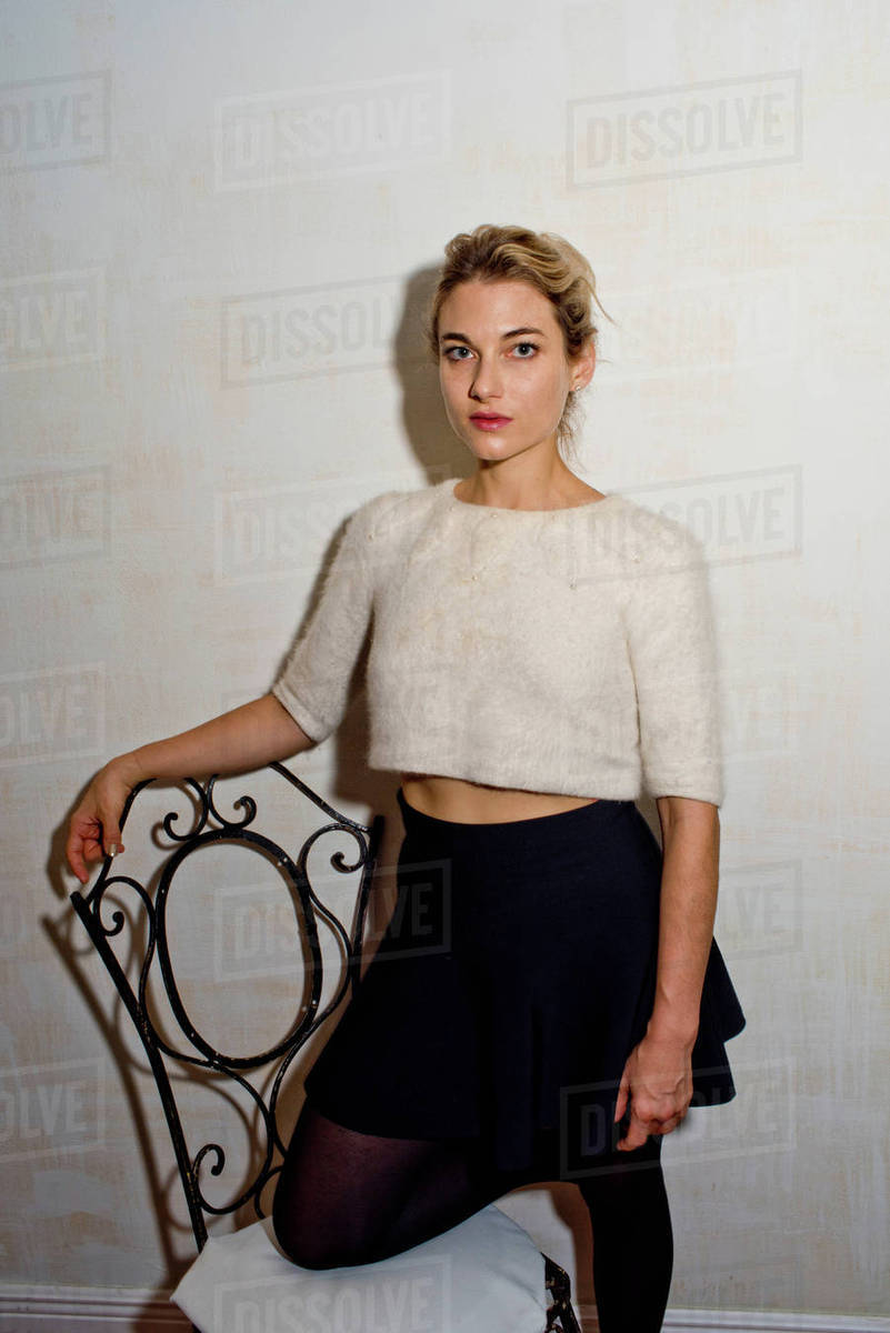 Portrait of woman leaning against chair looking at camera Stock Photo