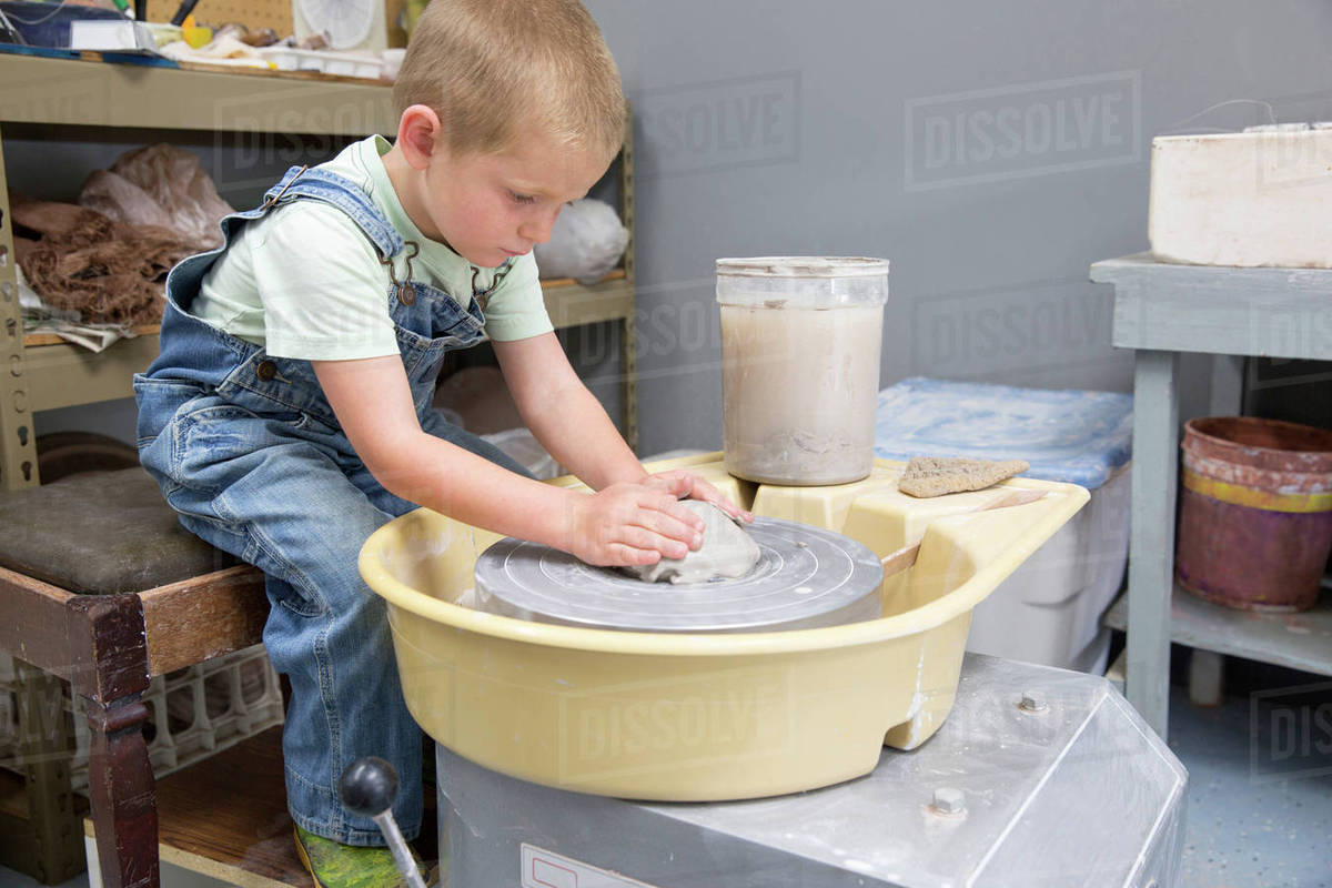 Boy shaping clay on potter's wheel Stock Photo Dissolve
