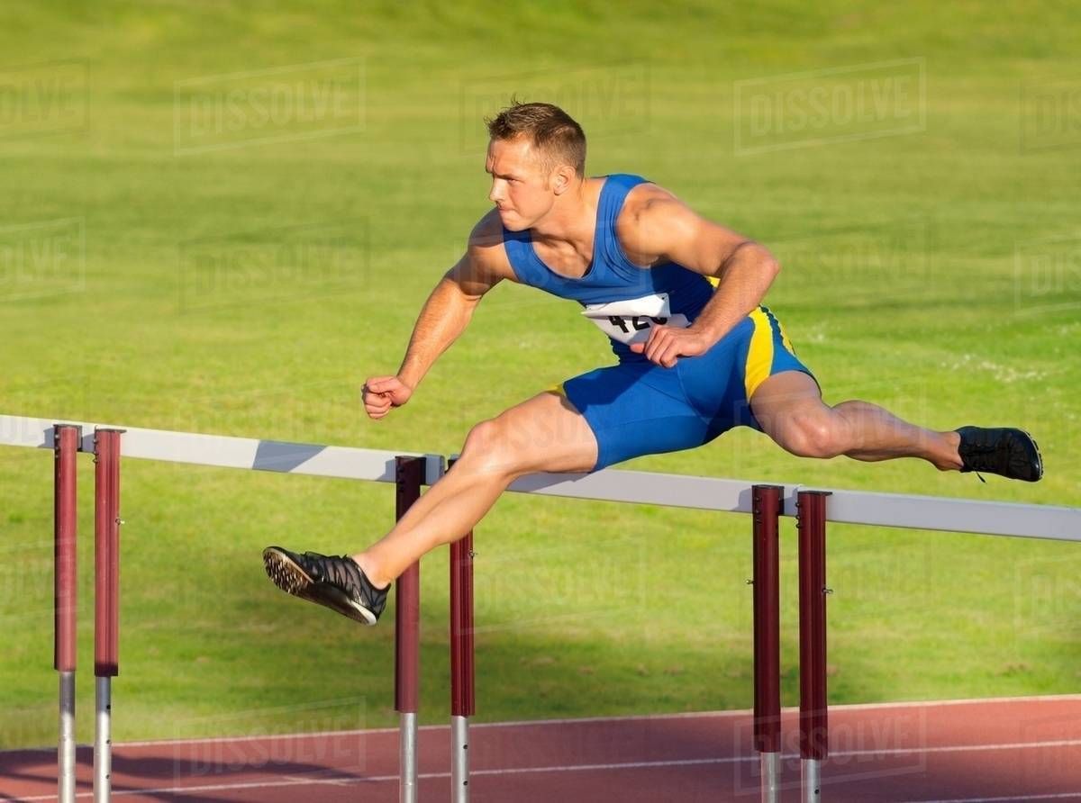 Male hurdler clearing hurdle Stock Photo Dissolve