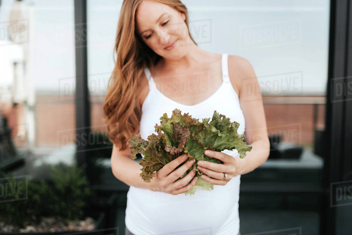 Pregnant woman admiring lettuce Stock Photo Dissolve