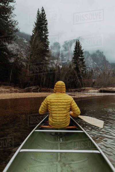 Young male canoeist rowing canoe on river, rear view, Yosemite Village ...