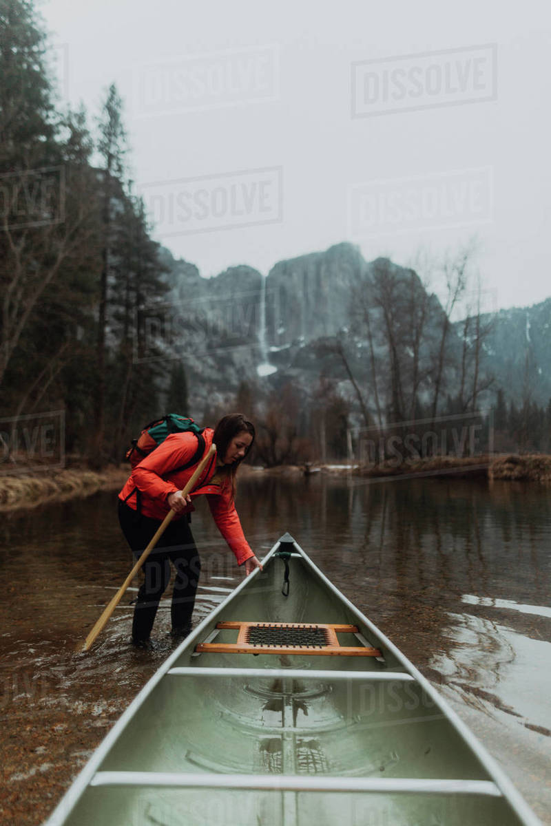 Young female canoeist pulling canoe in river, Yosemite Village