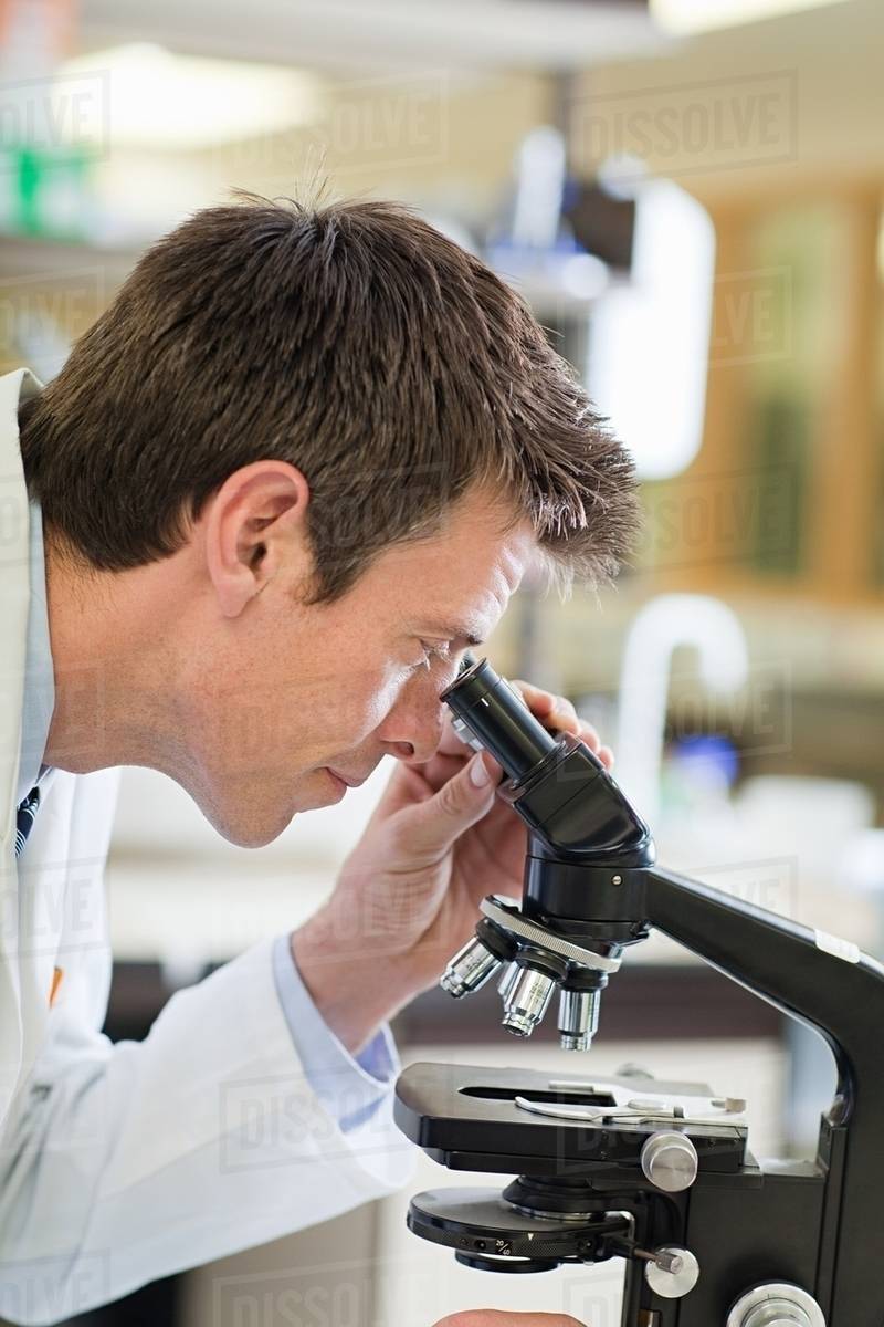 Doctor using microscope Stock Photo Dissolve
