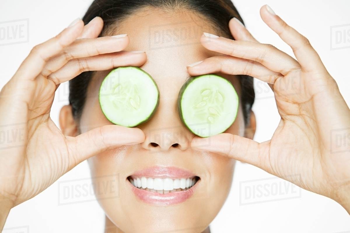 Woman holding cucumber over eyes Stock Photo Dissolve