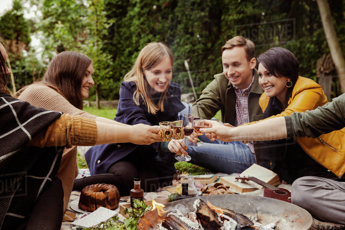 Group of friends toasting around fire pit in garden Stock Photo