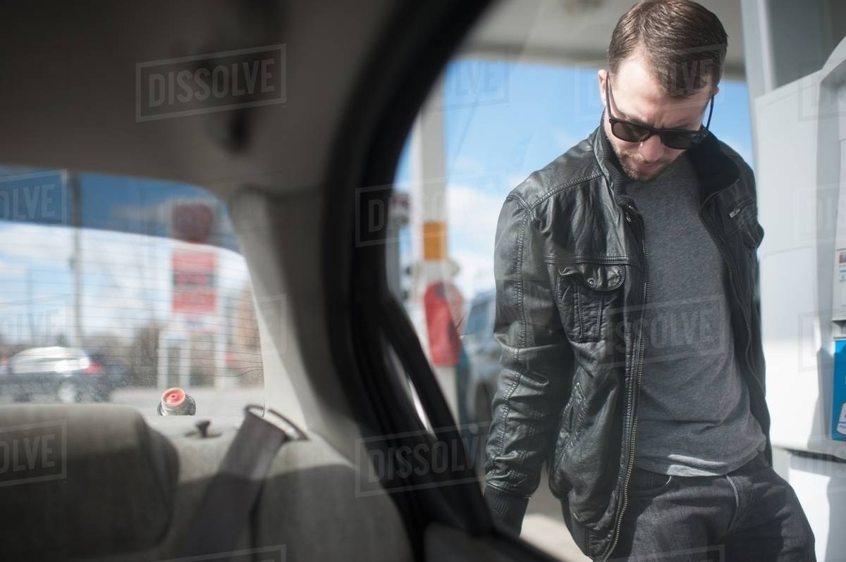 Young man putting fuel in car, view from vehicle interior Stock Photo