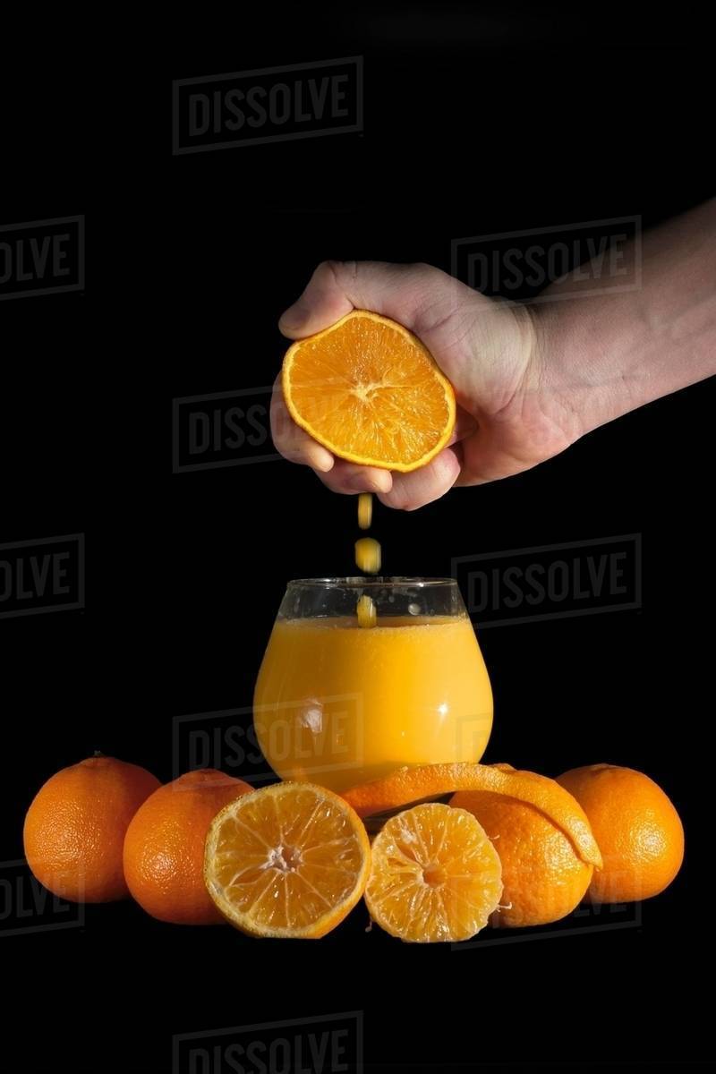Hand squeezing oranges into drinking glass Royalty-free Stock