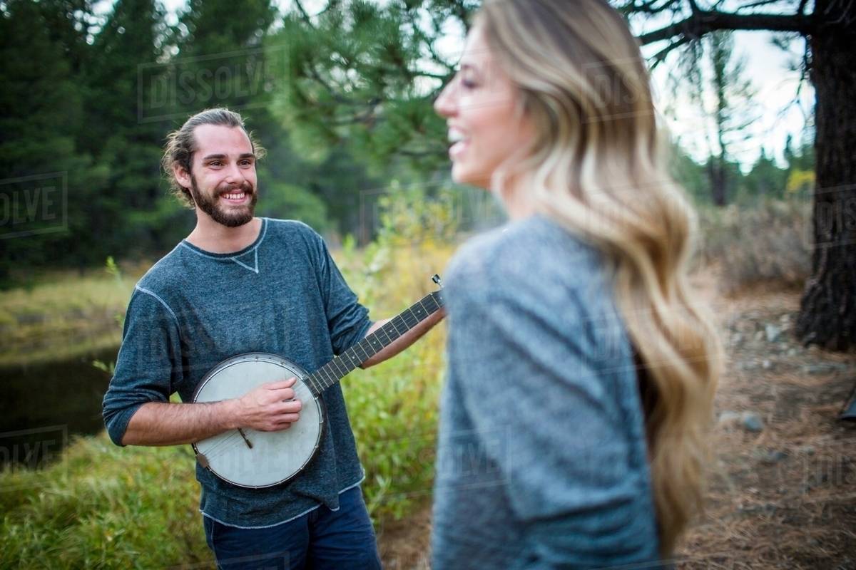Young couple playing banjo at riverside, Lake Tahoe, Nevada, USA