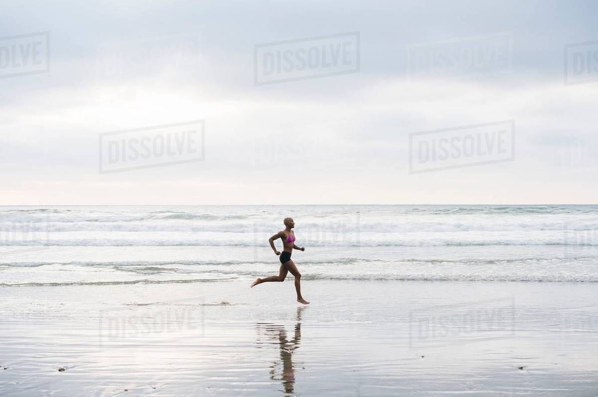 Woman in bikini jogging on beach Stock Photo Dissolve