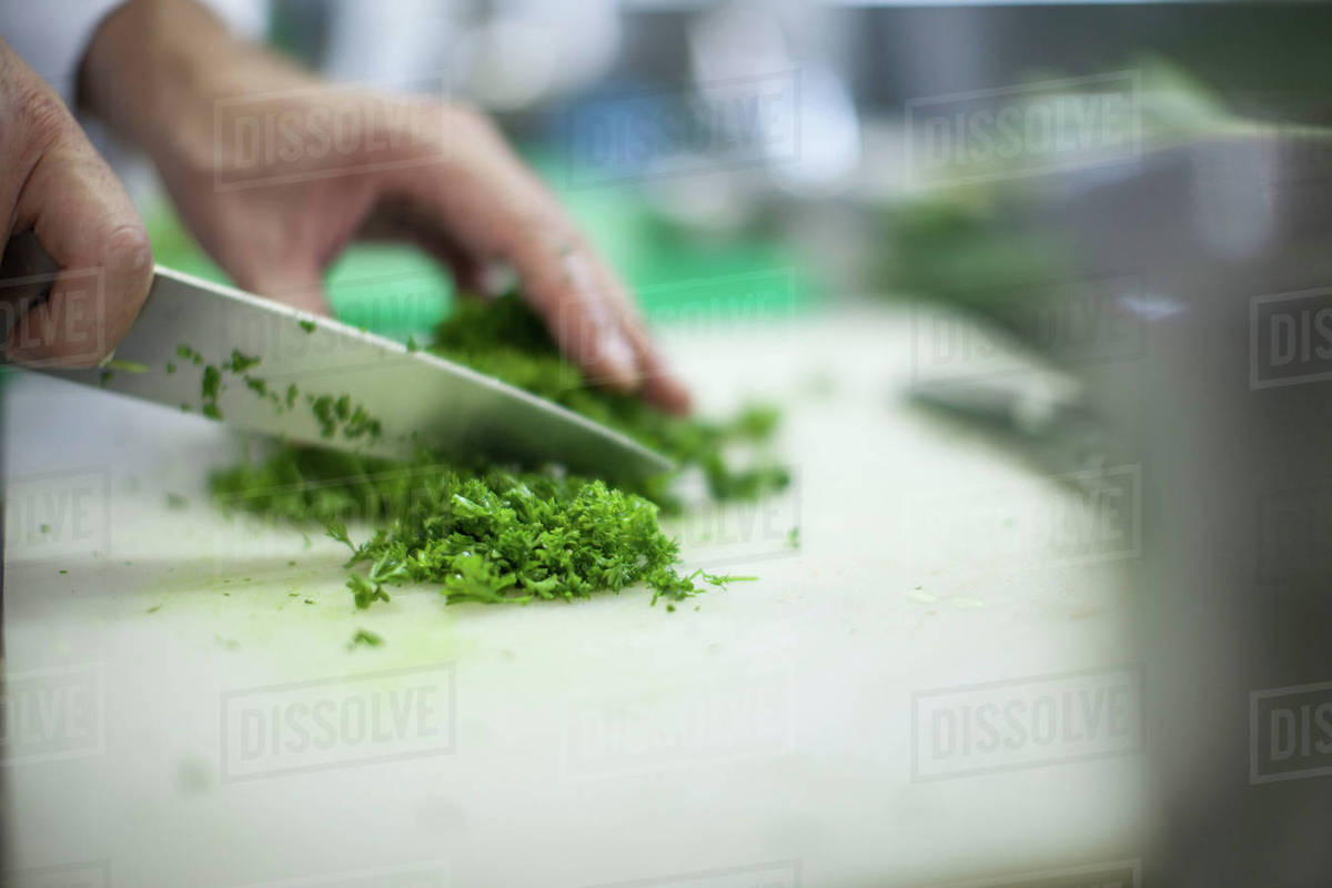 Chef chopping fresh herbs on table Stock Photo Dissolve