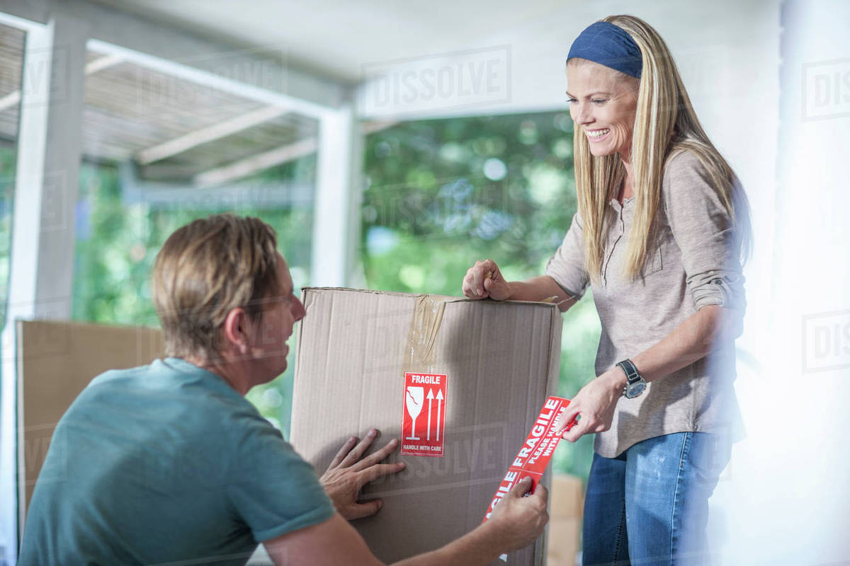 Moving house couple marking boxes with fragile stickers Stock Photo