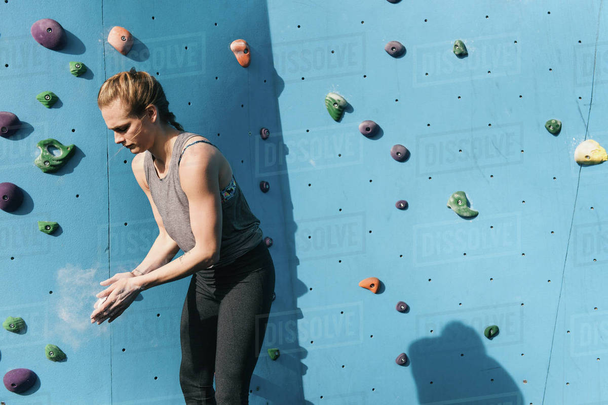 Young woman dusting hands, preparing to use climbing wall, Brooklyn