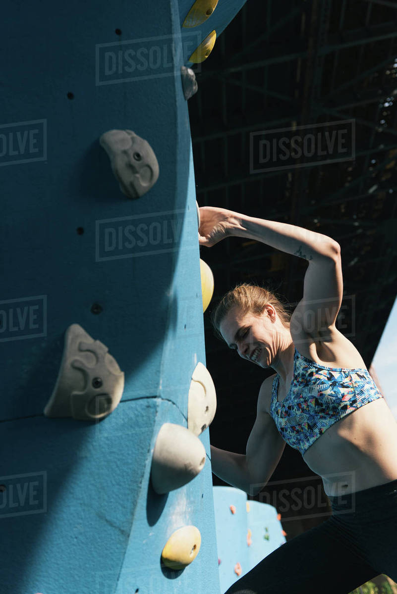 Young woman on climbing wall, Brooklyn Bridge Park, Brooklyn, New York