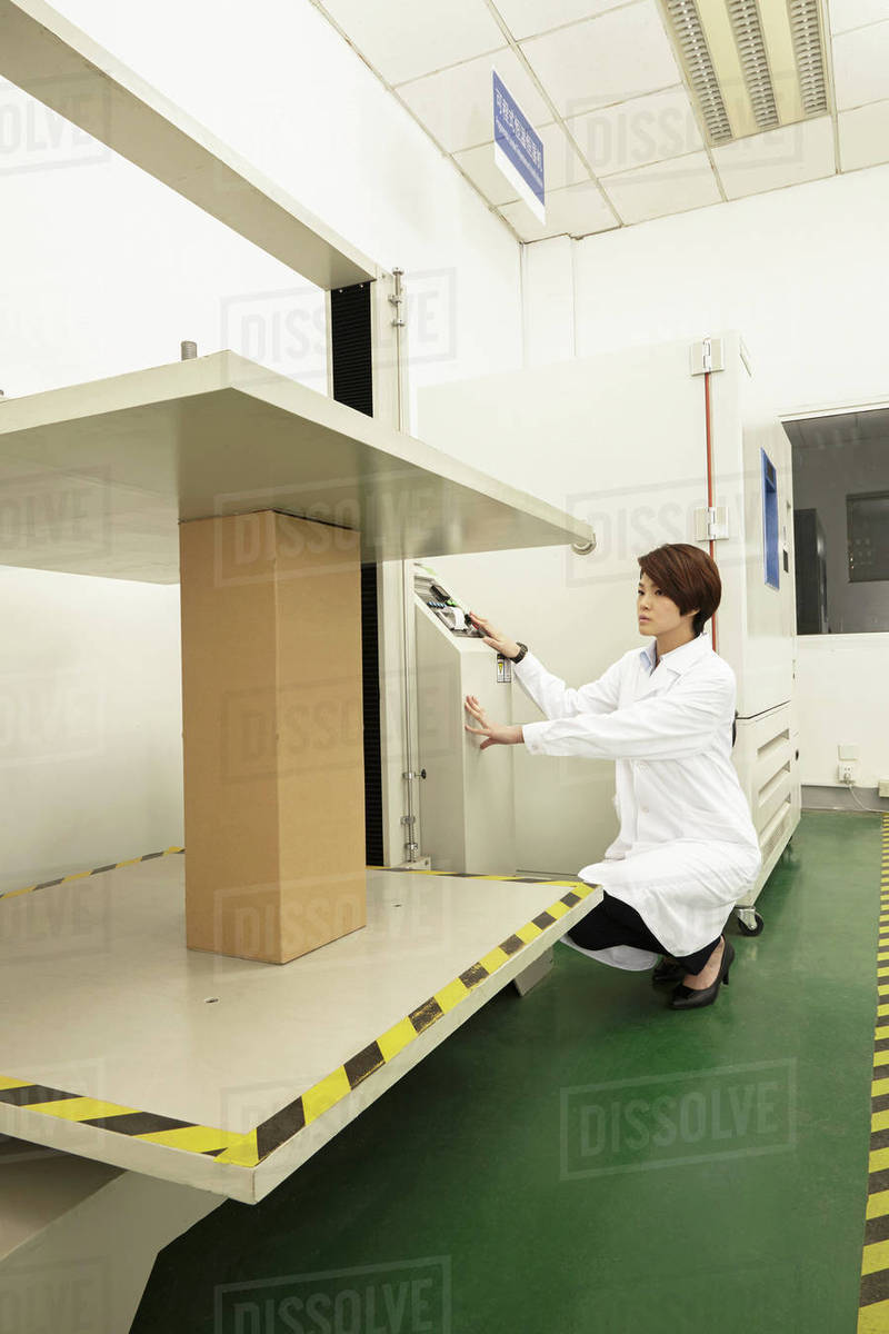 Female technician operating packaging machine in printing and packaging