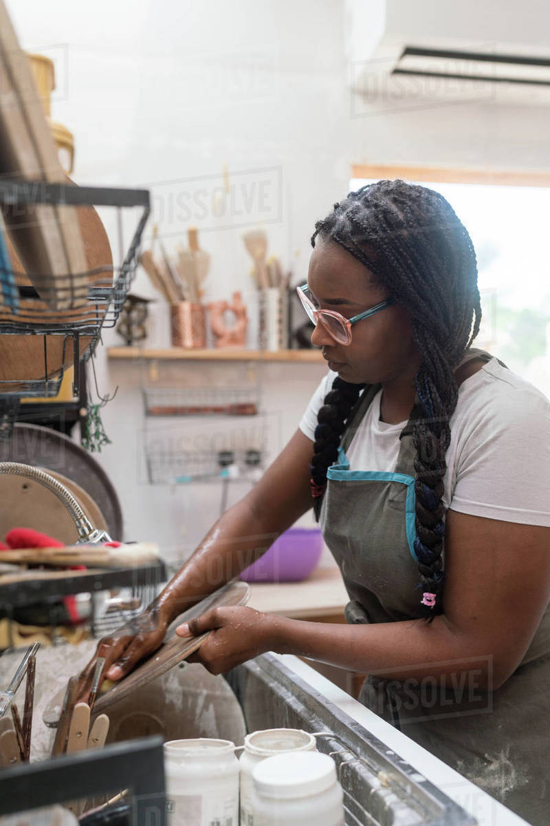 Woman washing her pottery at the ceramics studio Stock Photo Dissolve
