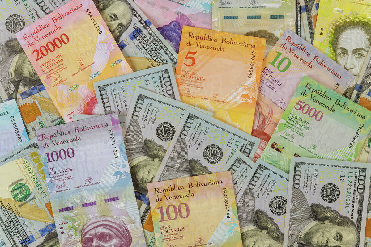 American dollar bills notes over Venezuelan Bolivar banknote with