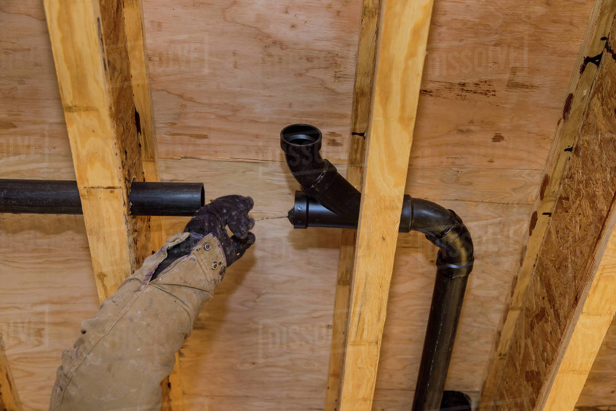 Worker is using glue with fitting for installing the PVC drain pipe in