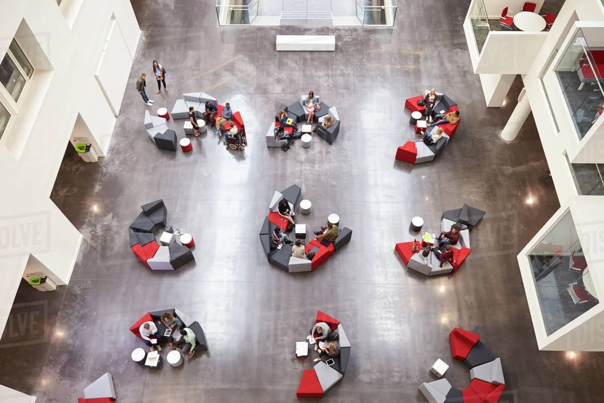 Student groups on seating in a modern university atrium Royalty