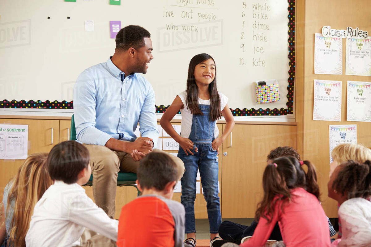 Schoolgirl At Front Of Elementary Class With Teacher Schoolgirl At Front Of Elementary Class With Teacher