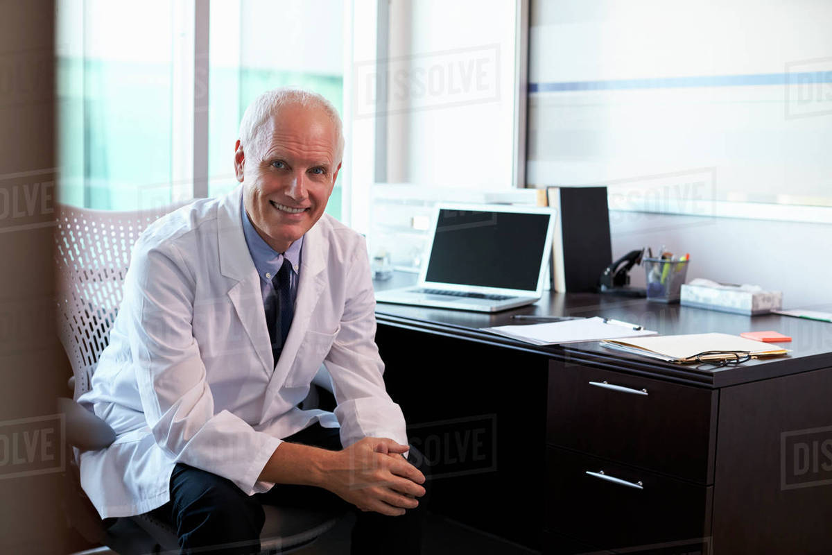 Portrait of doctor wearing white coat in office Stock Photo Dissolve