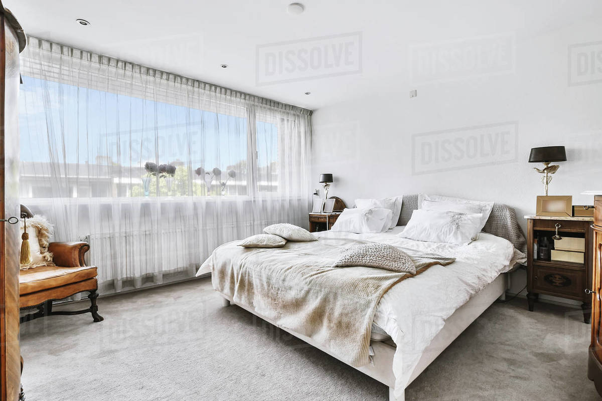 Simple interior of modern bedroom with queen size bed with cushions and ...