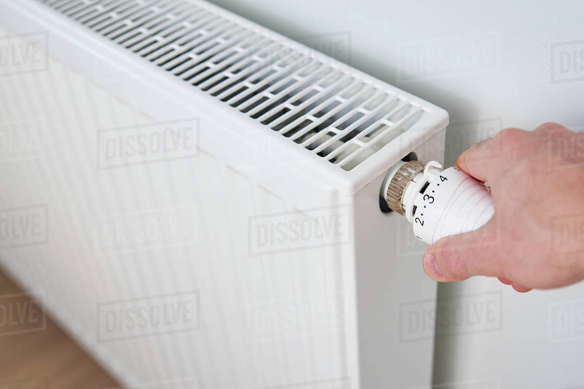 Hand adjusting temperature on heating radiator thermostat, Turning heat