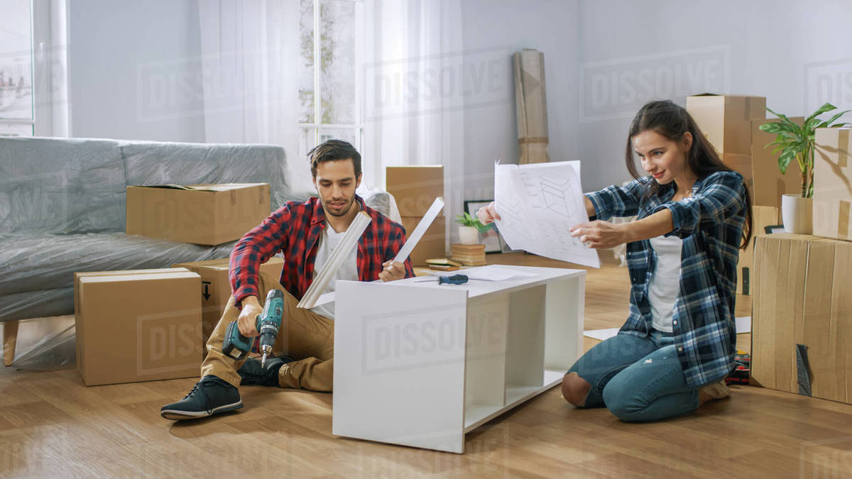 Funny and confused couple assemble furniture as a team, girl tries to ...