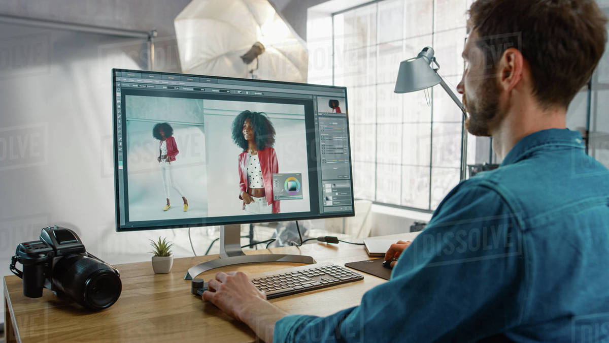Professional Photographer Sitting at His Desk Uses Desktop Computer in