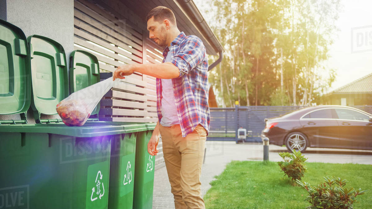 Man throwing away trash next to his house Stock Photo Dissolve