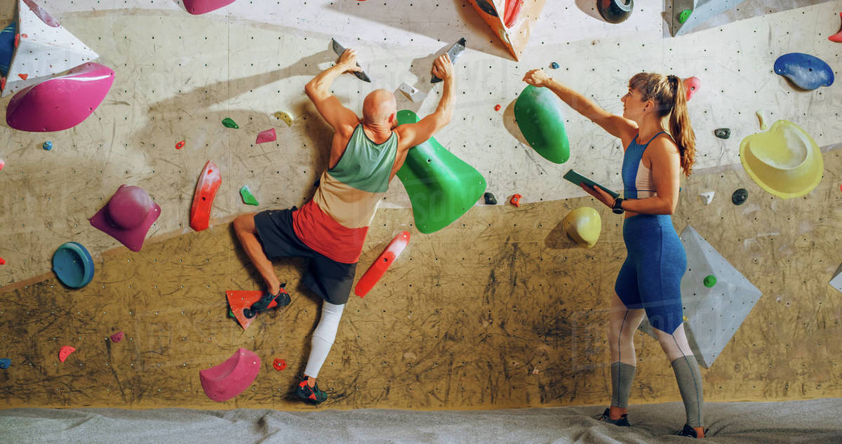 Rock Climbing Instructor Giving Lesson to a Beginner on a Bouldering