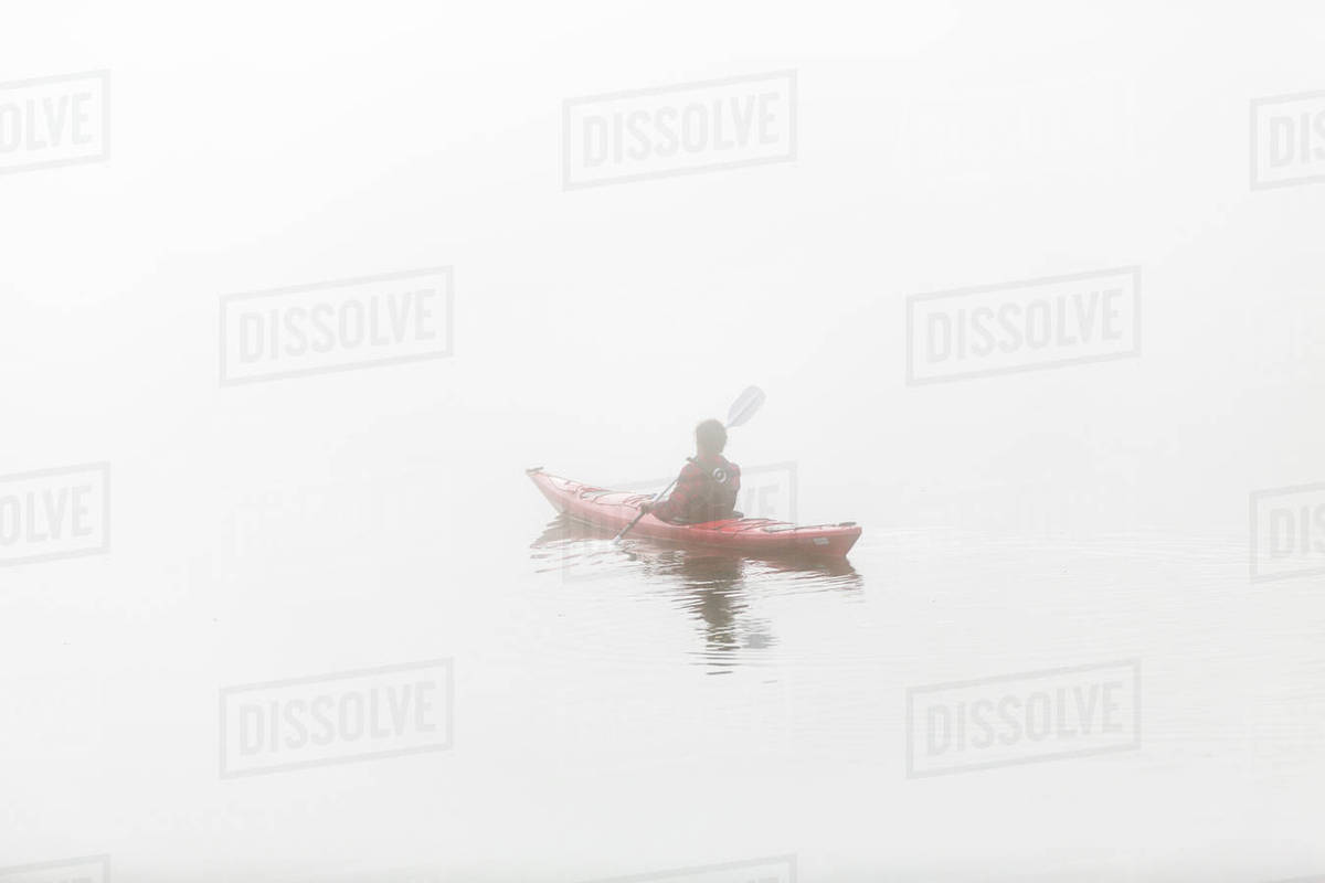 Person kayaking in fog Stock Photo Dissolve