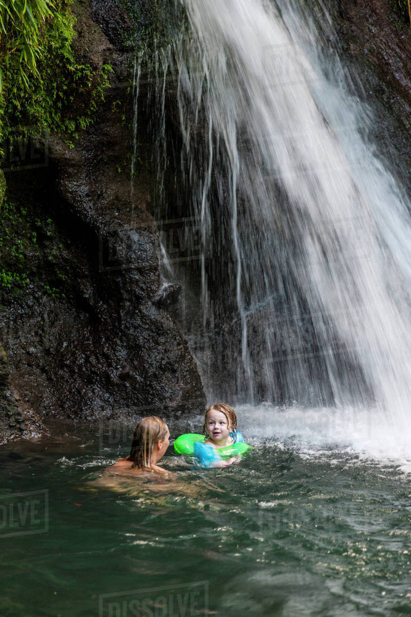 Mother with daughter swimming under waterfall Stock Photo Dissolve