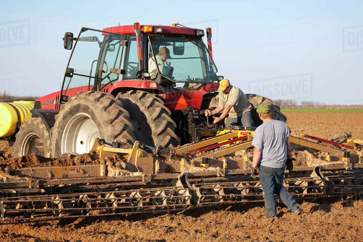 Agriculture Three farmers work to set up a secondary tillage implement during field