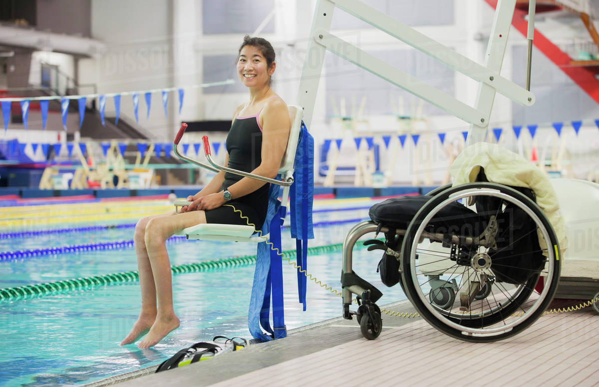 a paraplegic woman enters a swimming pool on a lift with her