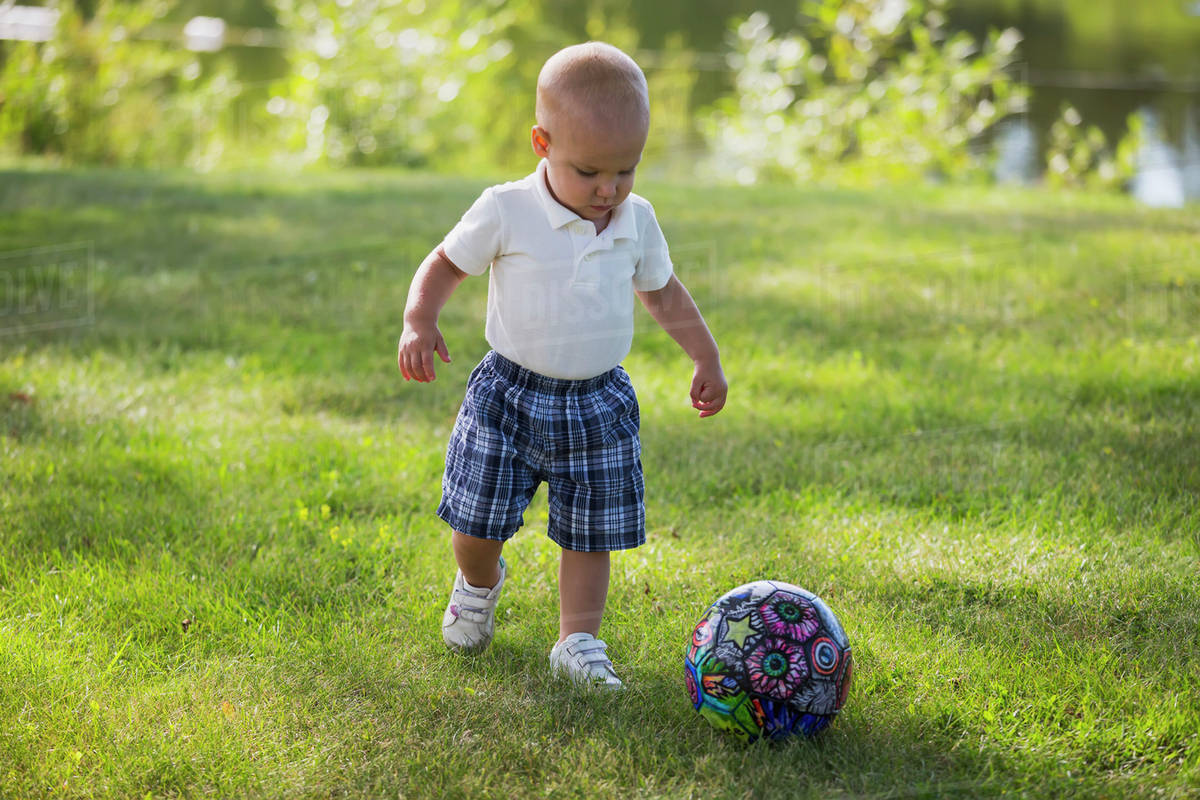 A toddler boy playing with a soccer ball in a park; Edmonton, Alberta