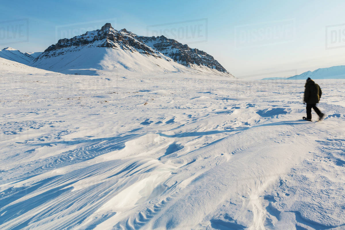 Man in a parka standing on the windswept snow, sastrugi patterns in the