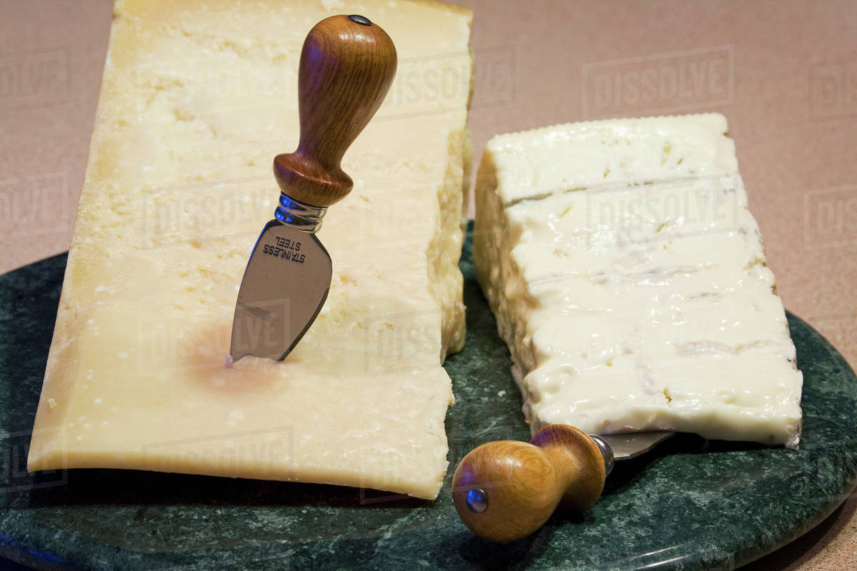 A block of parmesan and cheese on a marble round board with
