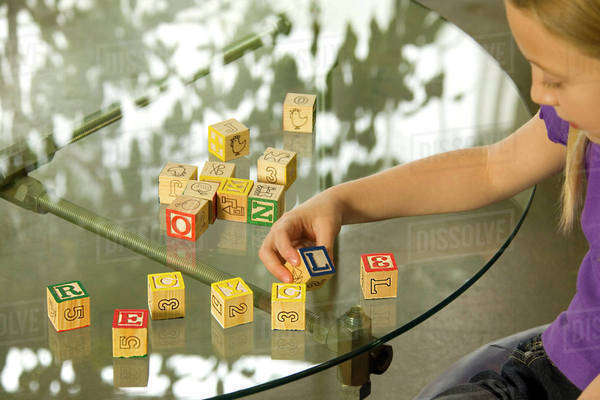 Young Girl Spelling Recycle With Alphabet Blocks - Stock Photo - Dissolve