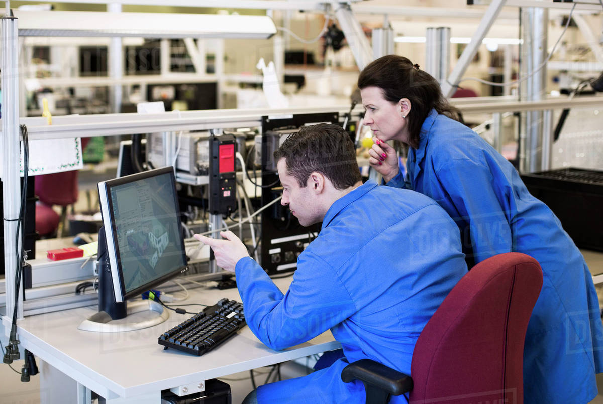 Male electrician pointing at computer monitor while discussing with ...