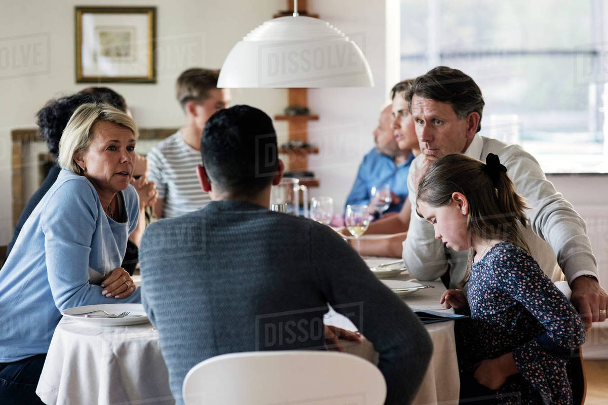 Multiethnic friends and family talking at dining table in dinner party