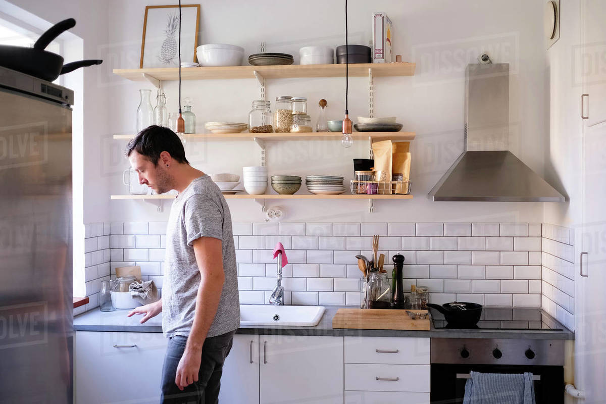 Side View Of Man Standing By Kitchen Counter At Home Stock Photo