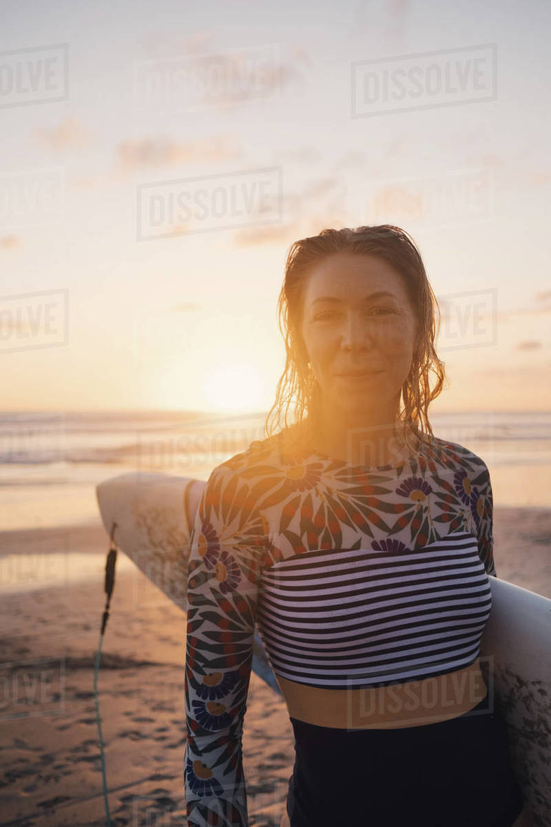 Portrait of confident woman with surfboard at beach during sunset Royalty-free stock photo