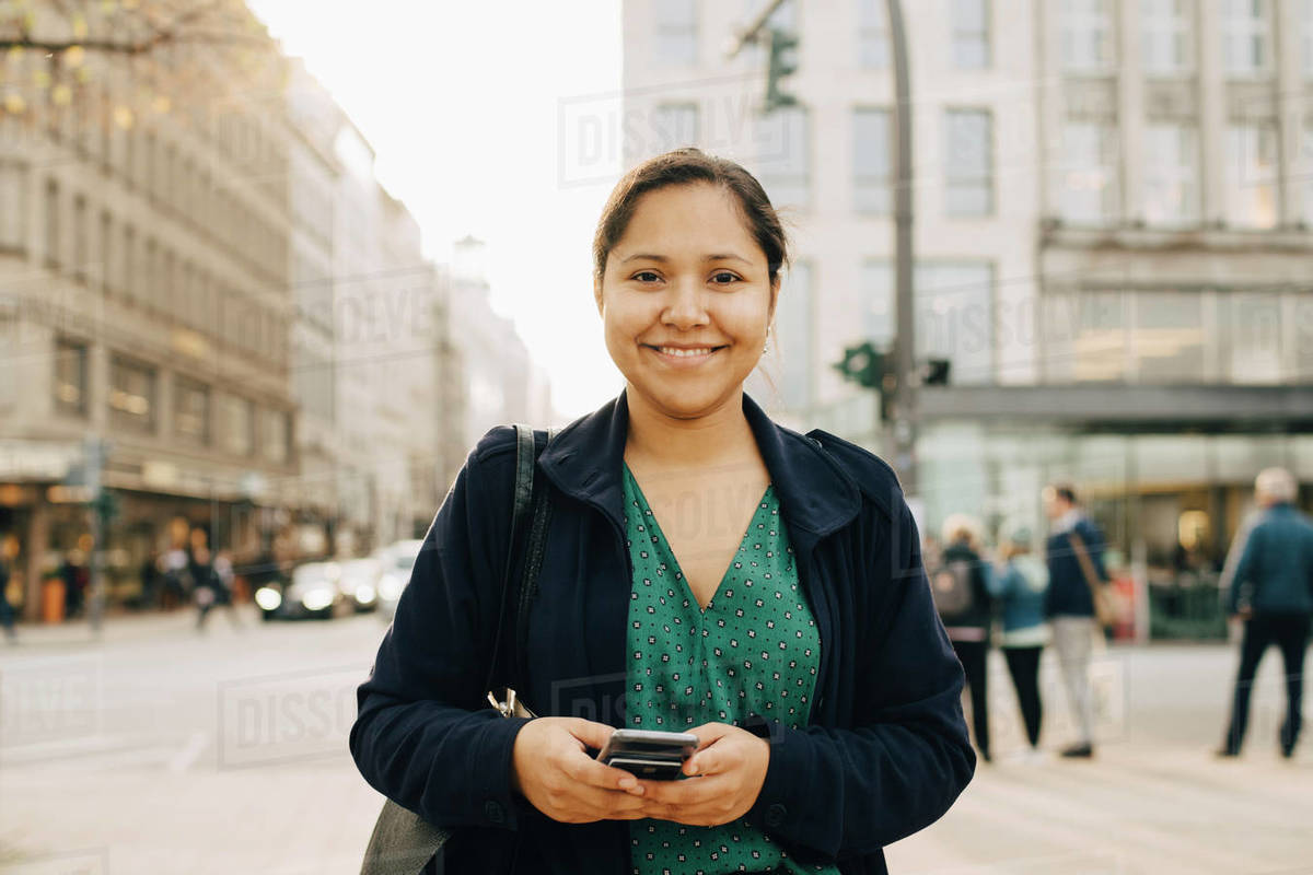 Portrait of smiling female entrepreneur with phone standing in city Royalty-free stock photo