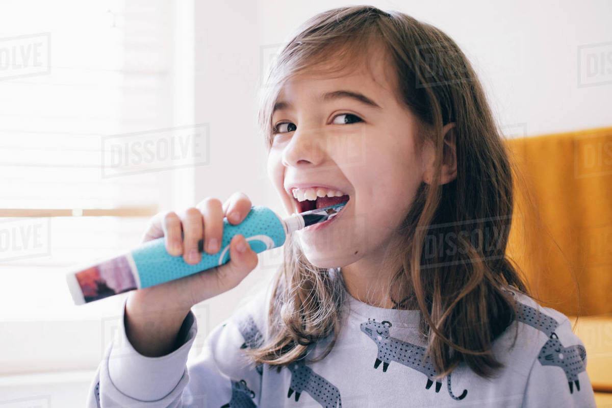 Happy girl with brown hair brushing teeth at home Stock Photo Dissolve