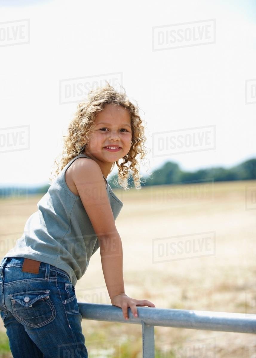Young girl on farm gate Stock Photo Dissolve