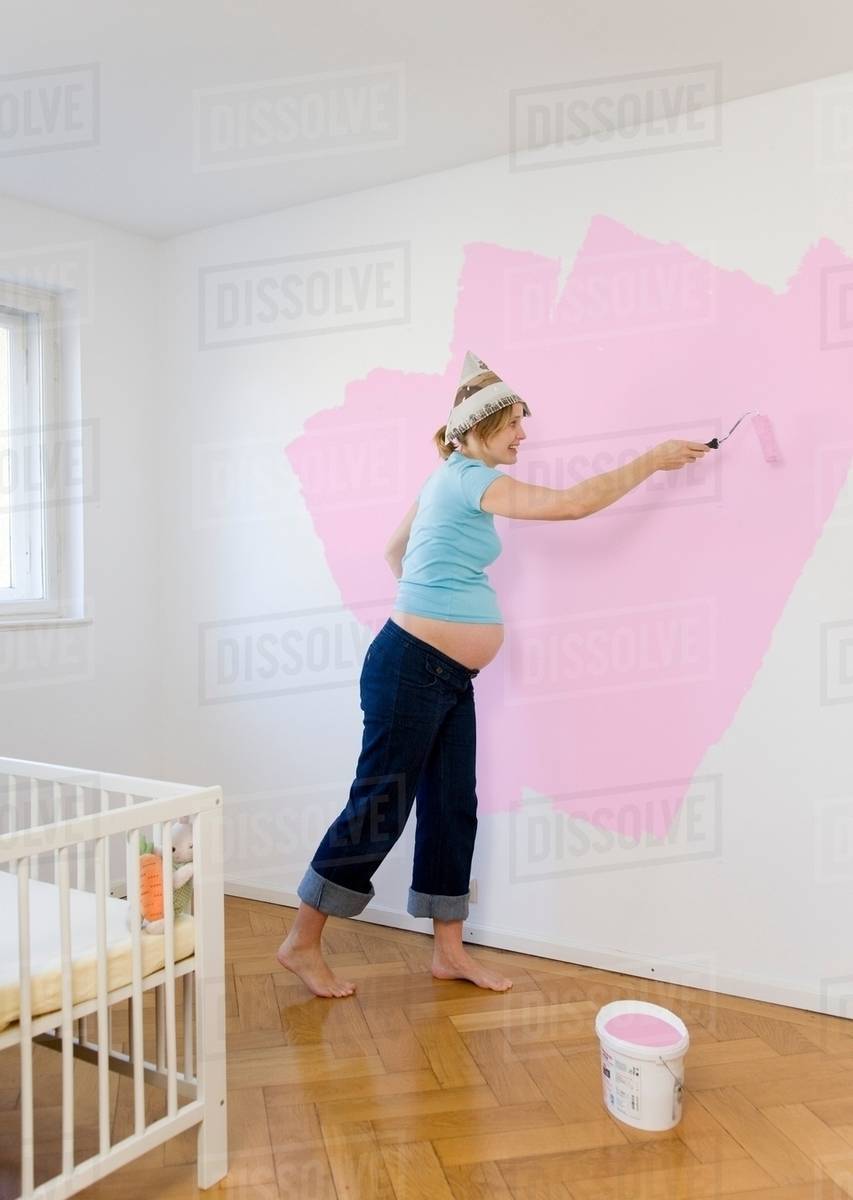 Pregnant woman painting nursery Stock Photo Dissolve